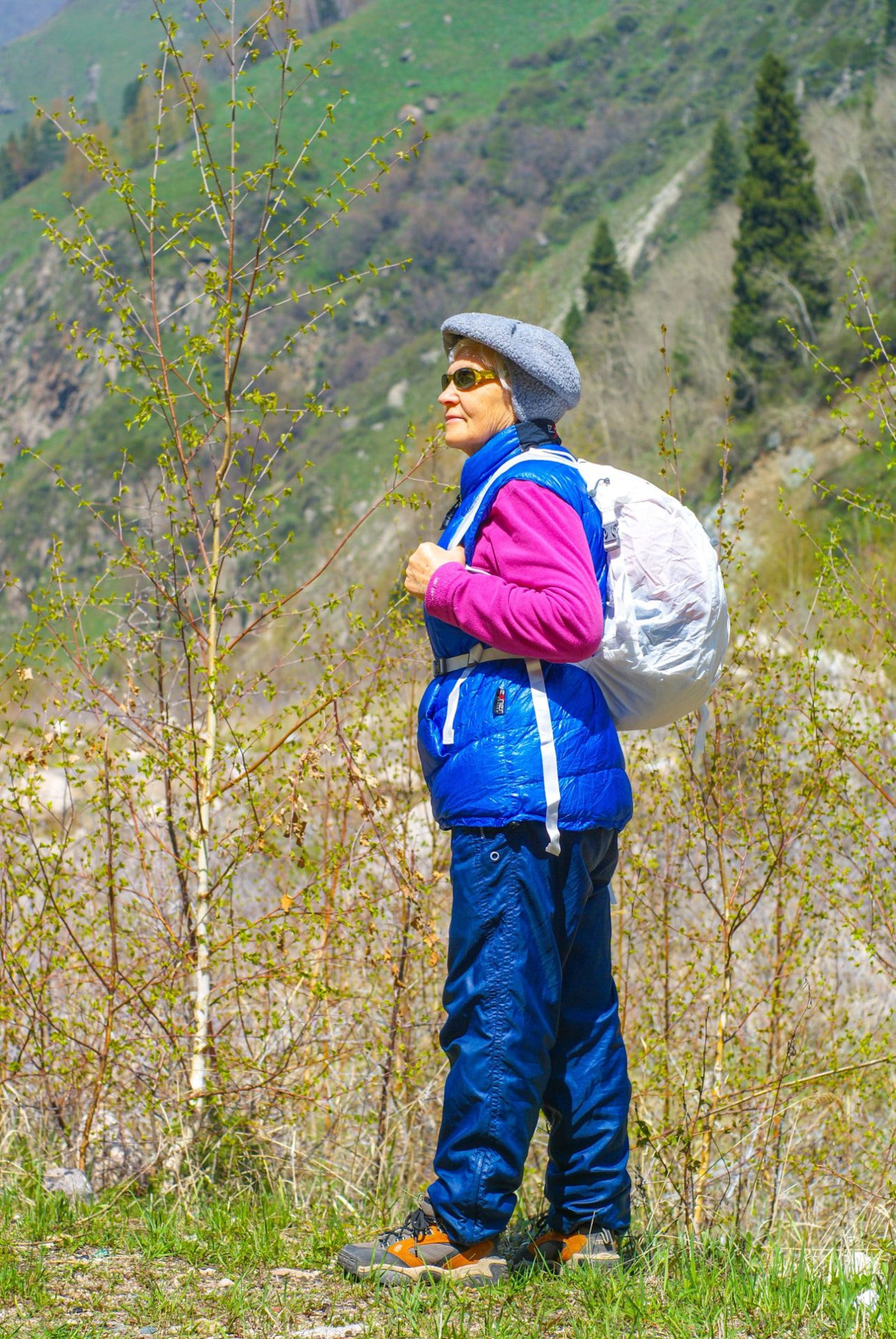 Member standing on a mountain trail with a backpack