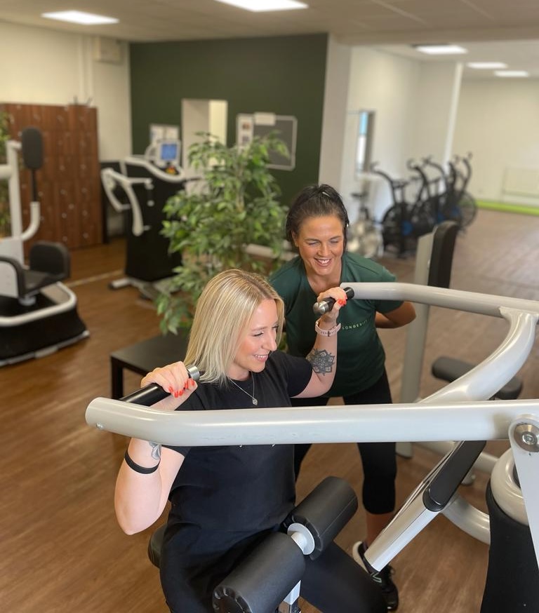 Trainer guiding an older member through a joint-safe strength machine